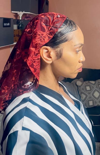 Woman in profile wearing a red lace headscarf and a black and white striped shirt.