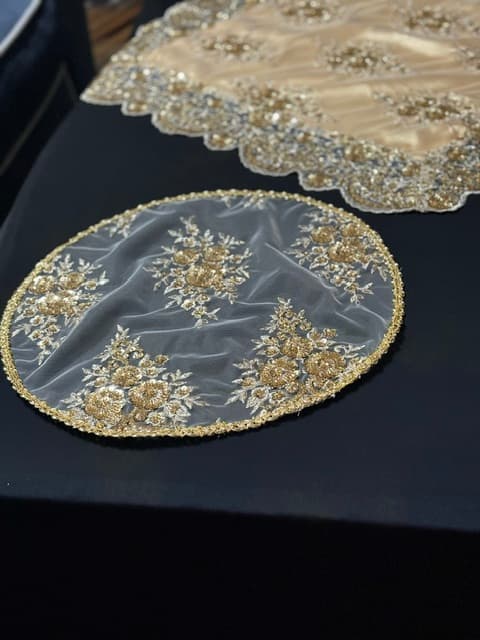 Elegant round sheer placemat with intricate gold floral embroidery and a scalloped gold border.